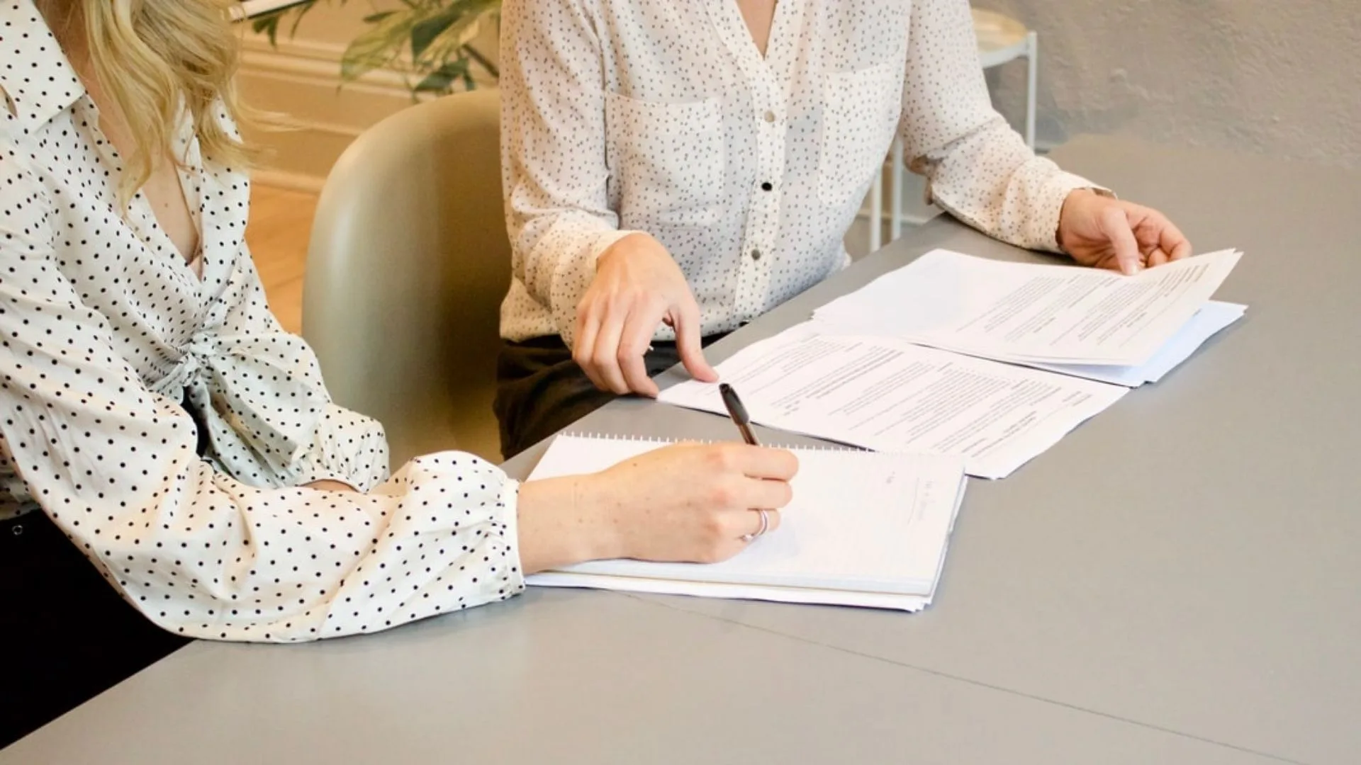 Two people reviewing and signing printed documents at a desk